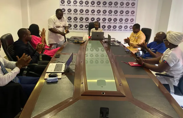 A team meeting around a boardroom table with laptops open